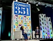 Two people seated in chairs on a stage at the Connect 351 conference.